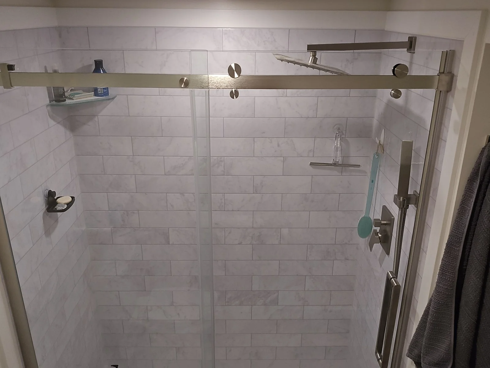 Marble subway tile shower with sliding glass doors