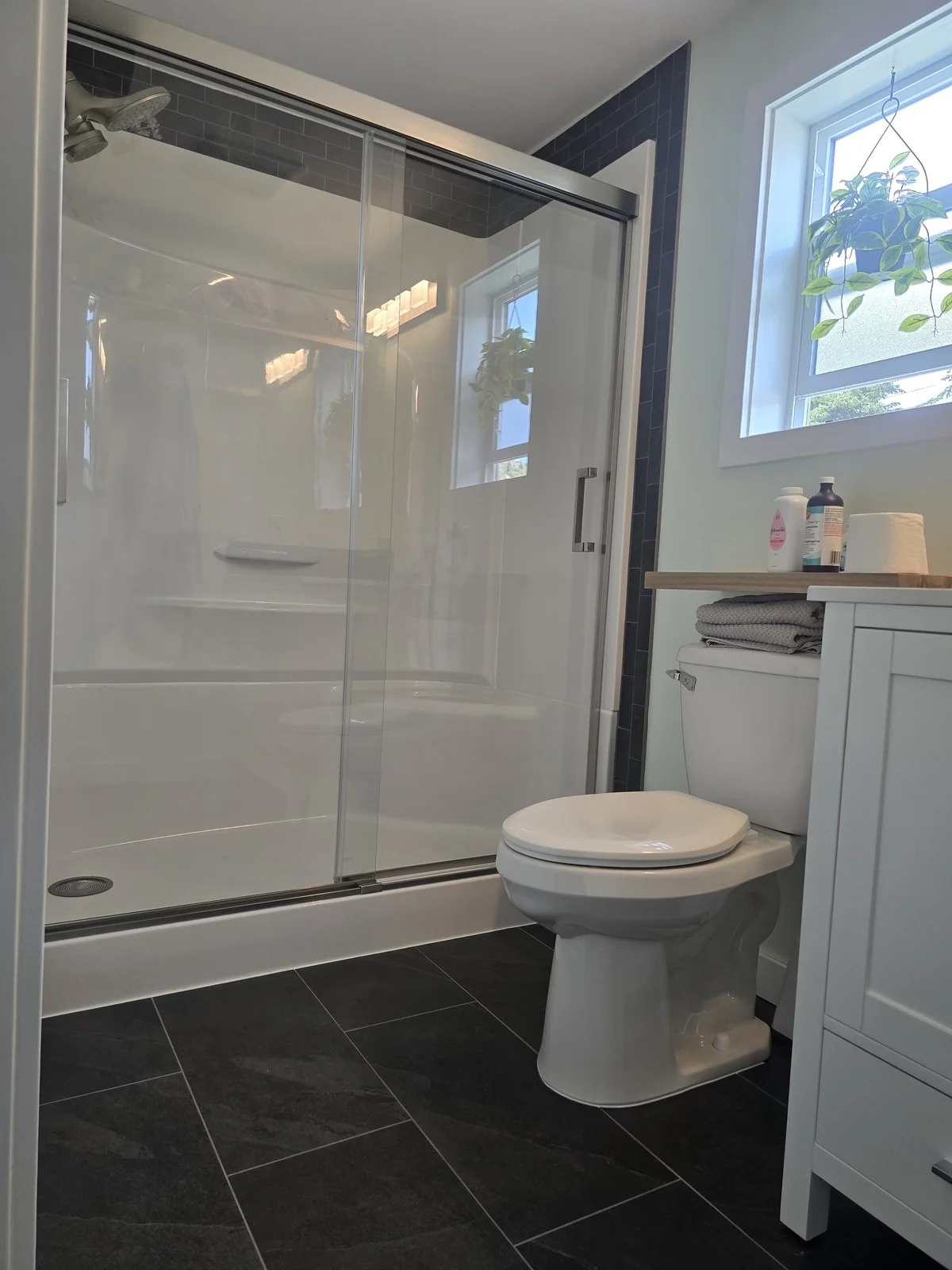 Bathroom with dark slate floor tile and a charcoal subway tile feature wall
