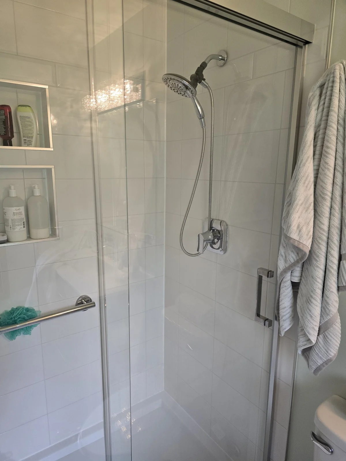 White tile shower with recessed niches and a glass door
