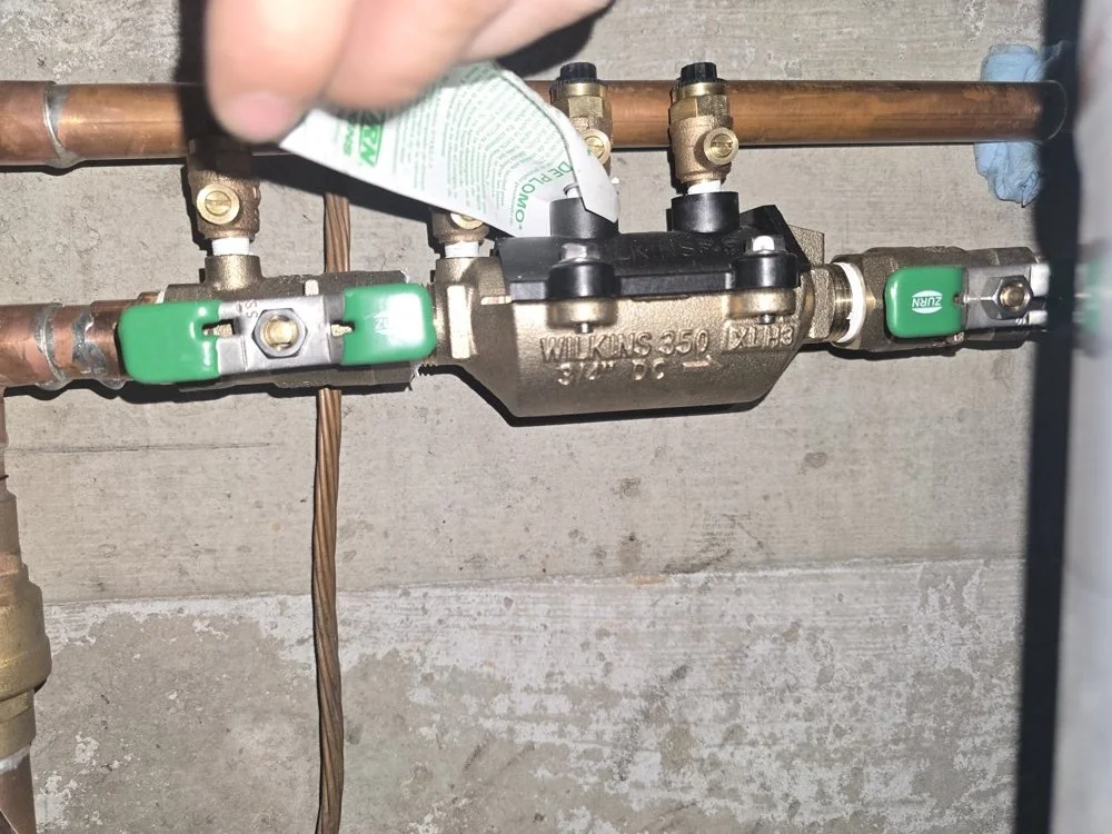 Red Seal plumber servicing a copper manifold and shut-off valves