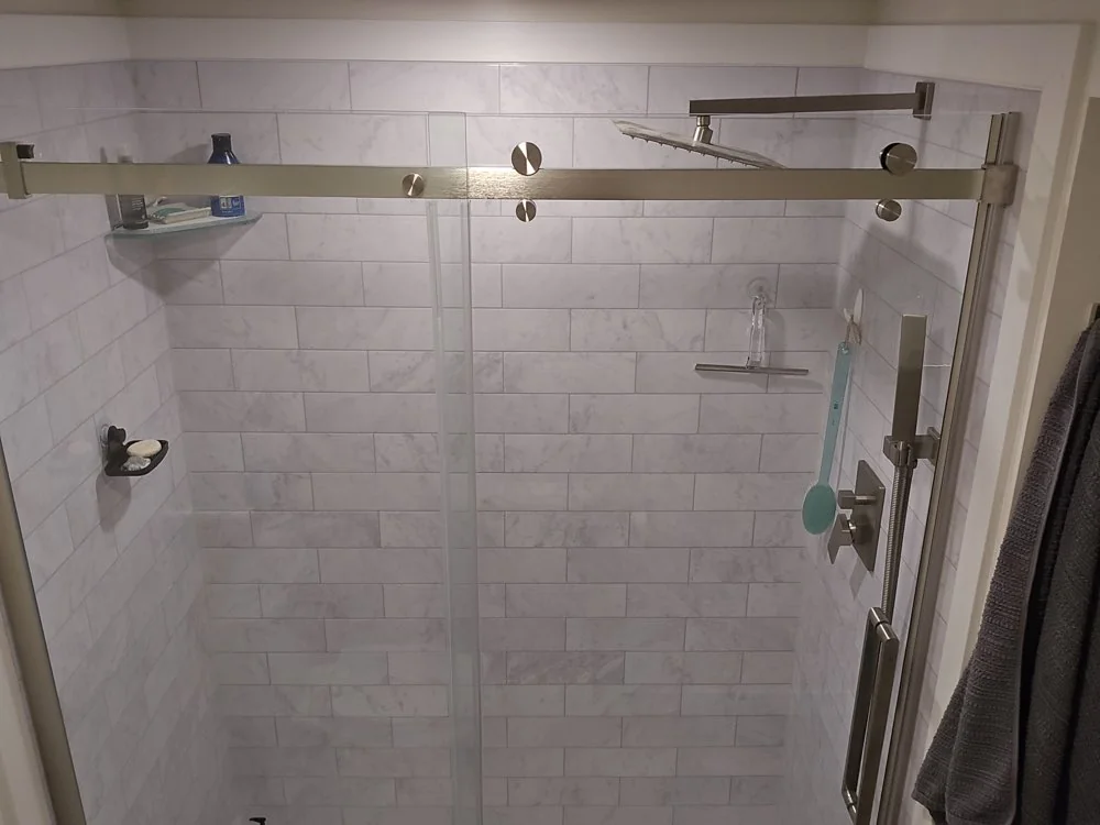 Marble subway tile shower with sliding glass door